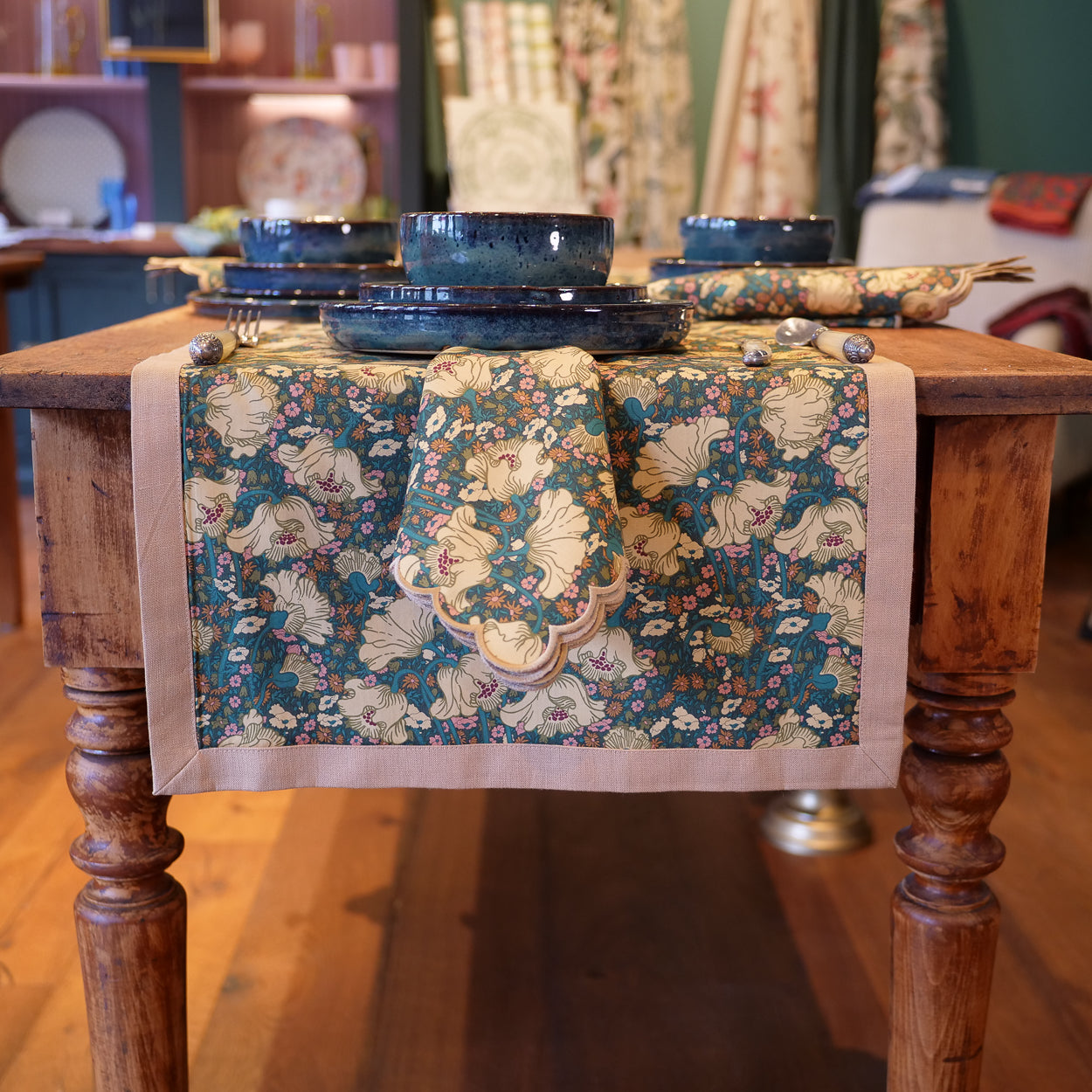 Floral-patterned table runner on a wooden table with blue bowls and silverware.