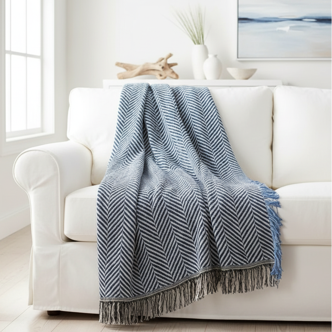 Blue and white striped throw blanket draped over a white sofa in a beachhouse.