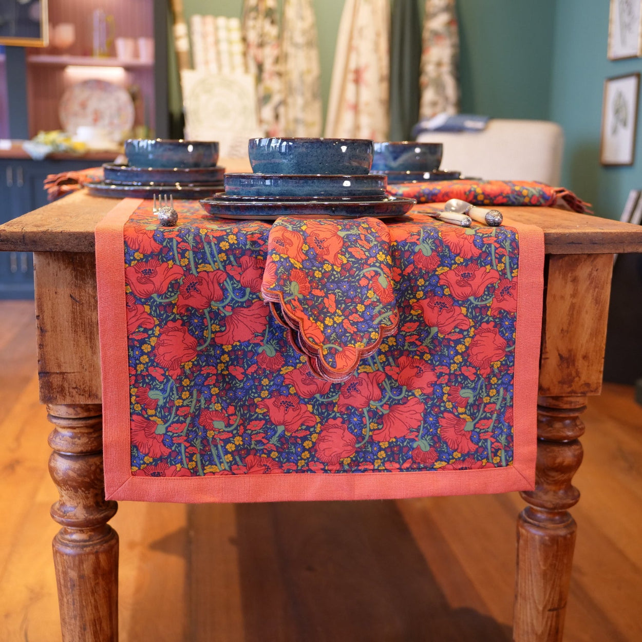 Colorful floral table runner on a wooden table with blue plates.