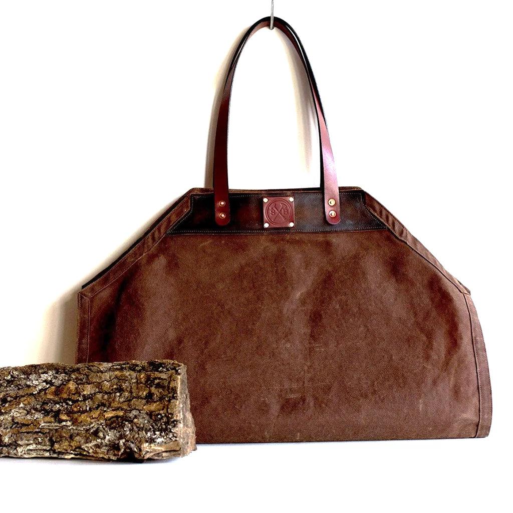 Nutmeg and brown colored waxed canvas and leather firewood carrier with a log