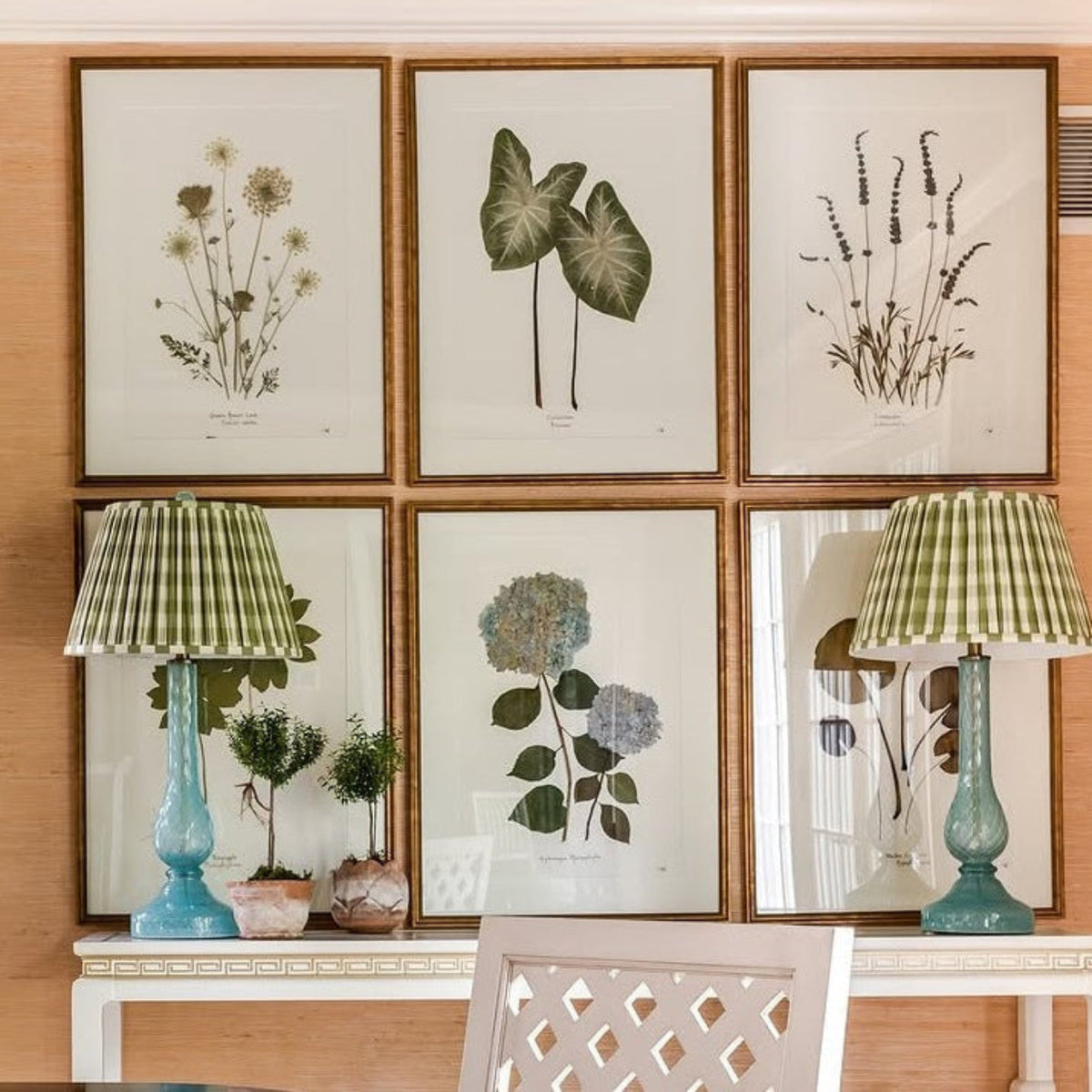 Framed pressed botanicals by Sandy Whitaker hung above a console table in a Southern dining room
