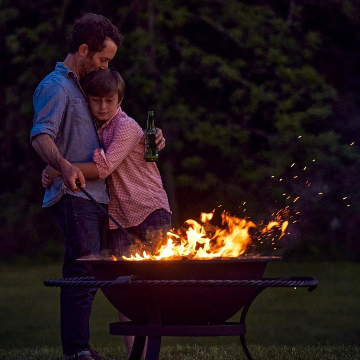 Man and child by a fire pit at night