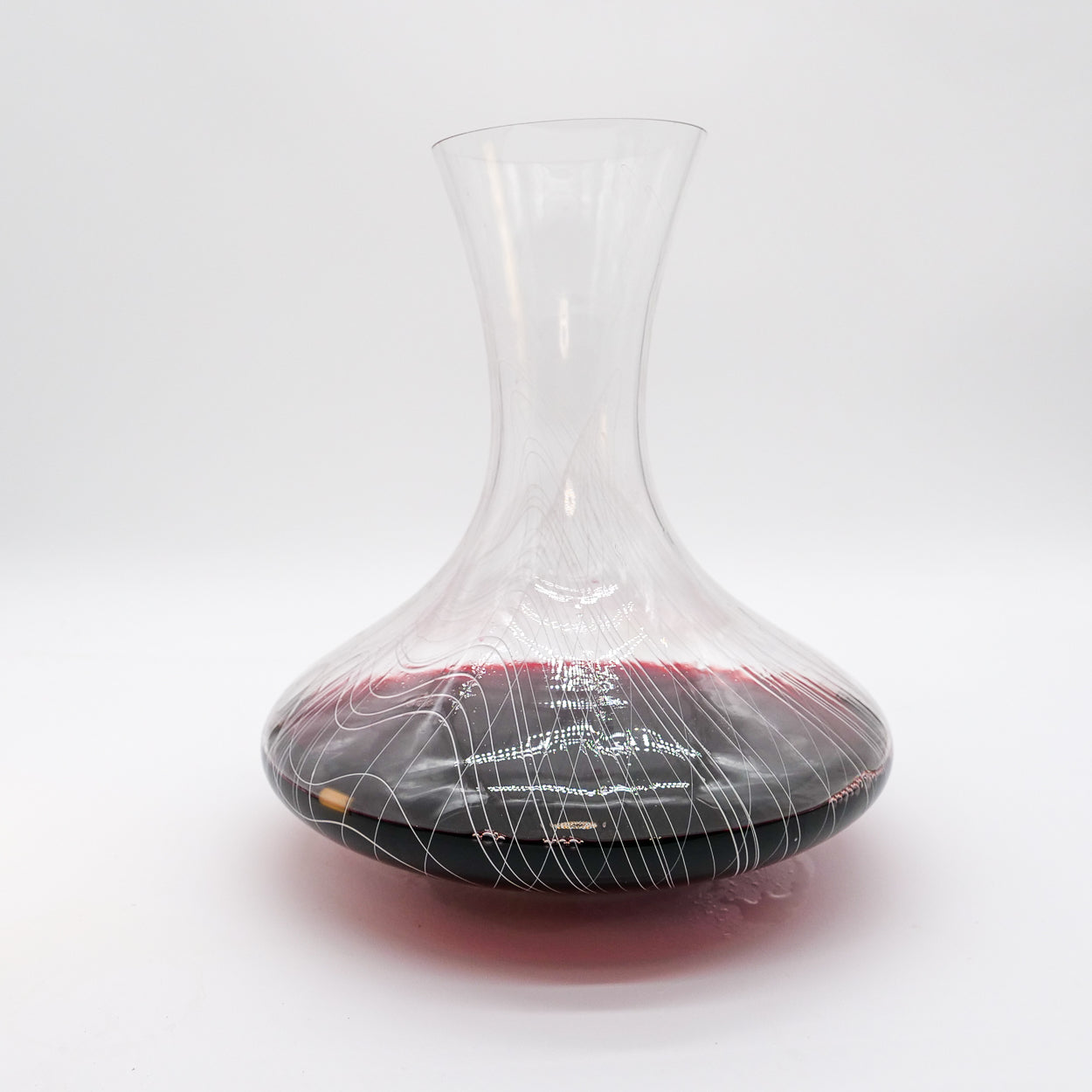 Clear glass wine decanter with red wine on a white background
