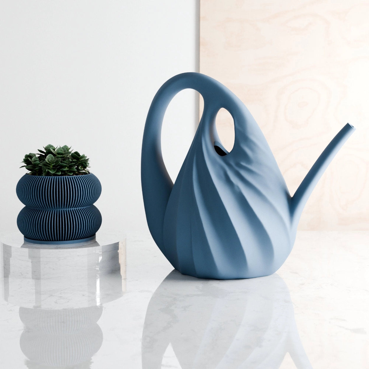 Blue ceramic watering can and decorative pot on a reflective surface with a light background
