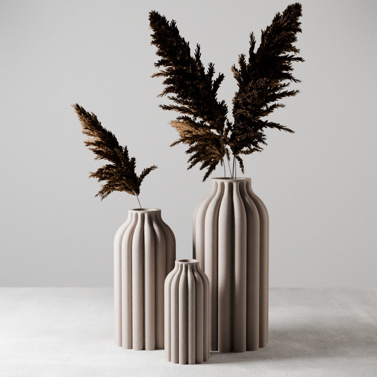 Three beige ceramic vases with dried pampas grass on a light gray background