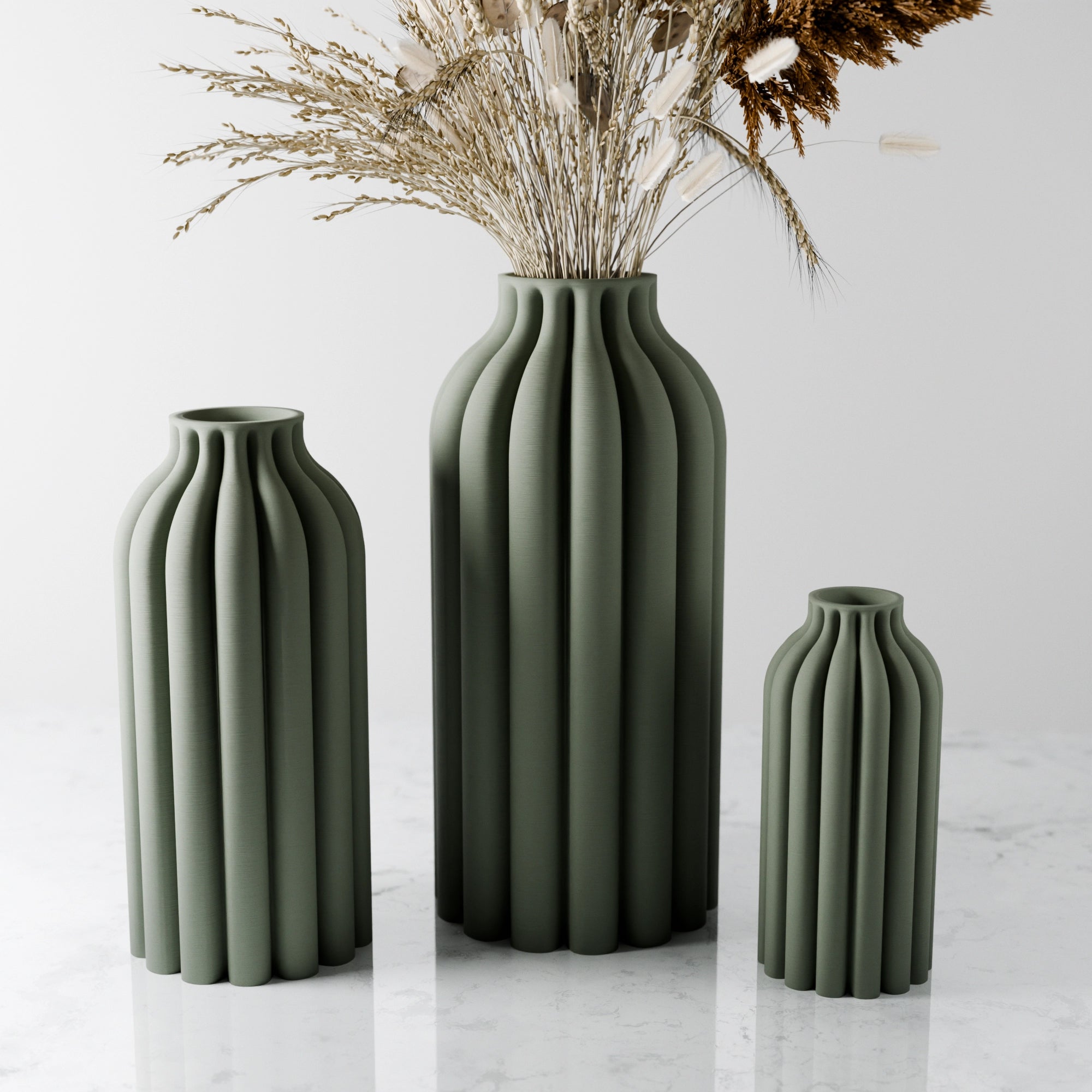 Three green ceramic vases of different sizes on a light background