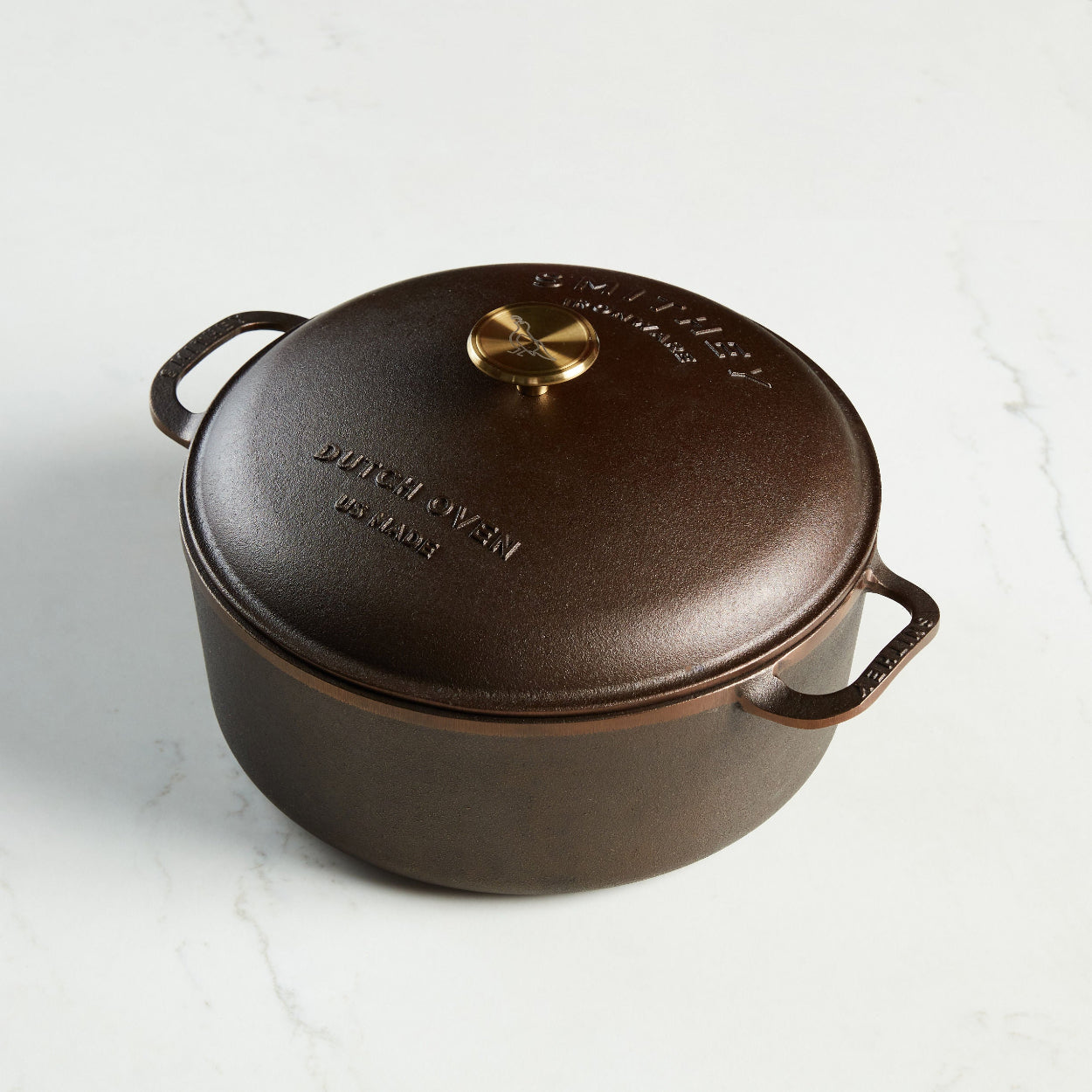 Smithey Cast Iron Dutch oven with a gold knob on a white background