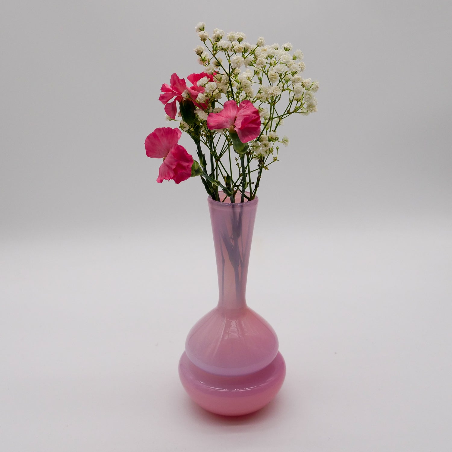 Pink vase with flowers on a light gray background