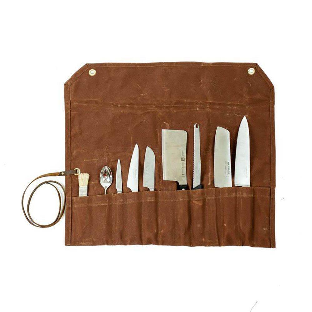 An open waxed canvas chef knife roll with kitchen knives